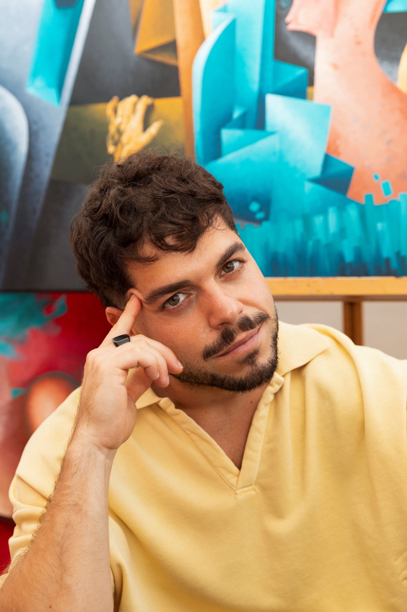 Man in a yellow shirt sitting in front of colorful abstract art